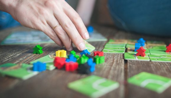 Best couples' board games - photo showing a player's hand moving tiles and pieces in a game of Carcassonne