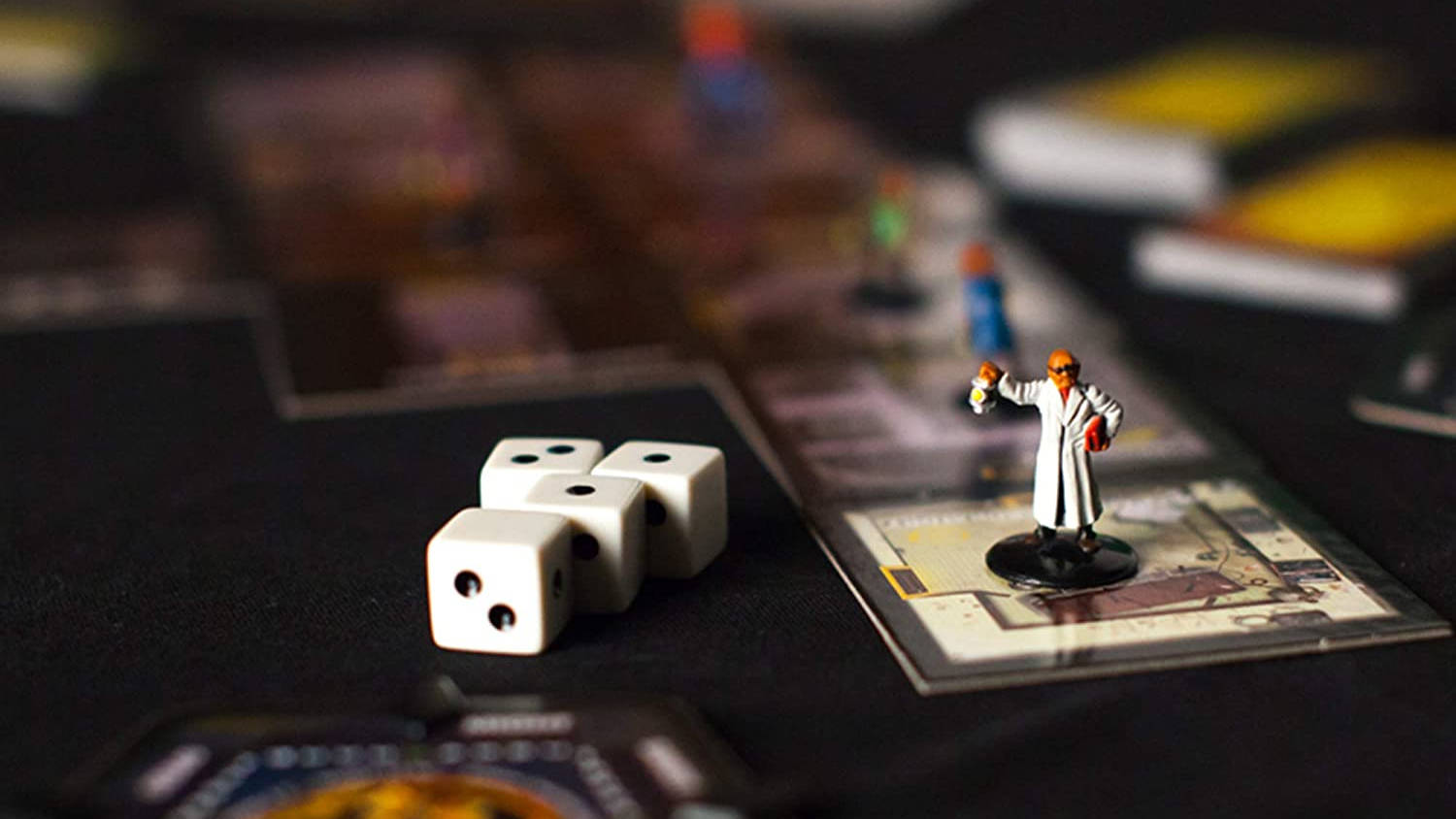 Fun board games Betrayal at House on the Hill miniature next to a collection of dice