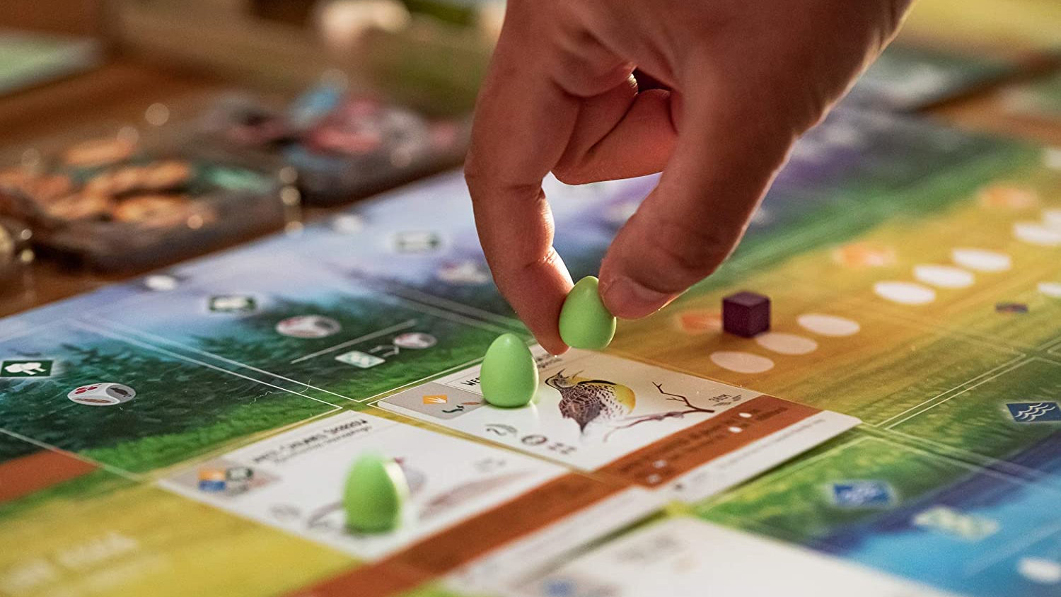 Best board games for Christmas a hand moving an egg onto a bird card from Wingspan