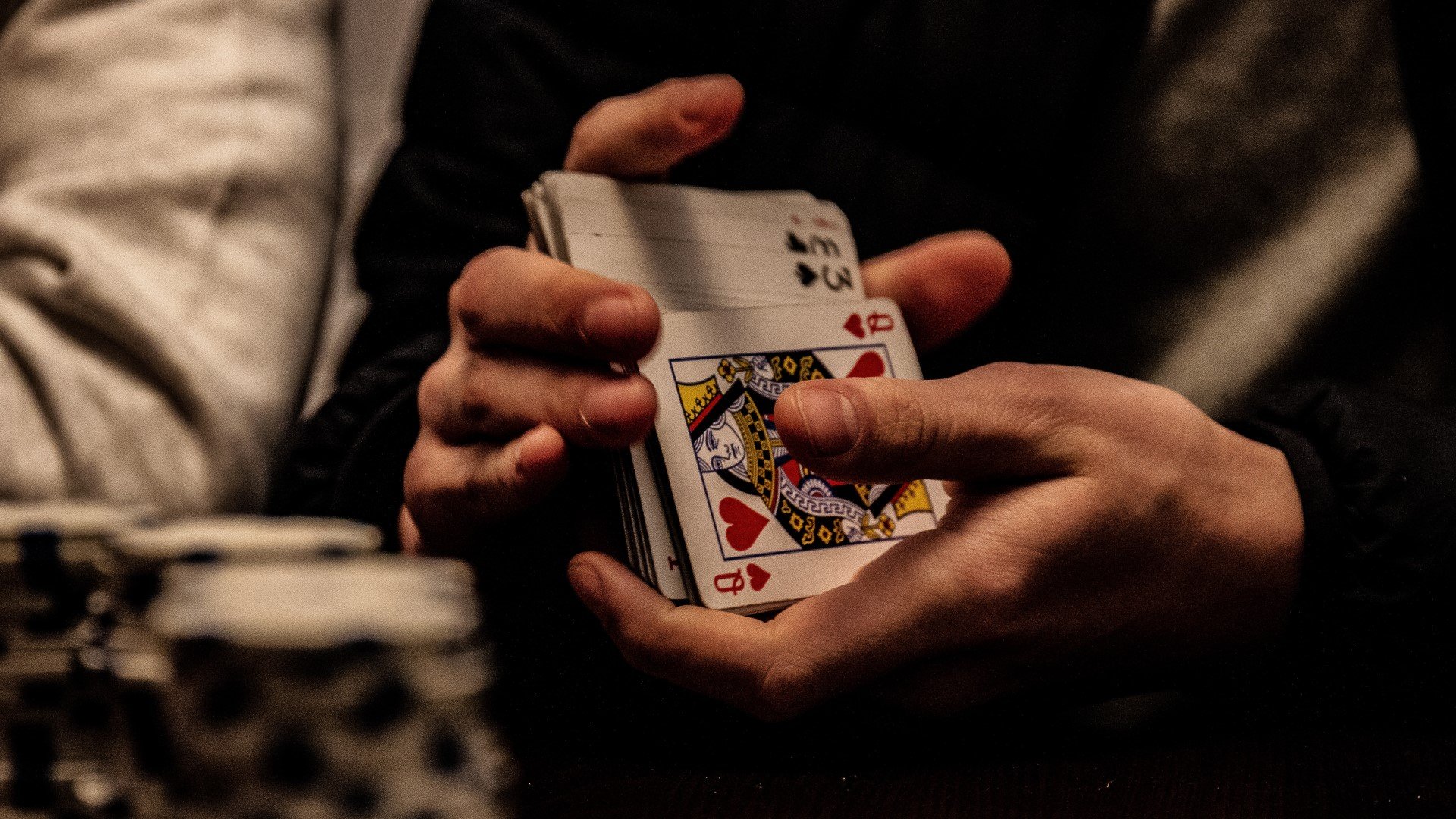 Drinking card games a man shuffling a pack of cards, credit to Unsplash Marin Tulard
