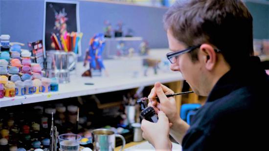 Games Workshop jobs talent programmes - Games Workshop corporate photo of an 'Eavy Metal painter painting a miniature
