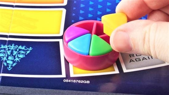 Best trivia board games guide - sales photo for Trivial Pursuit showing a player's hand placing a wedge into their cheese mover