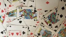 Playing card games: A deck of playing cards spread across the floor in a dense layer.