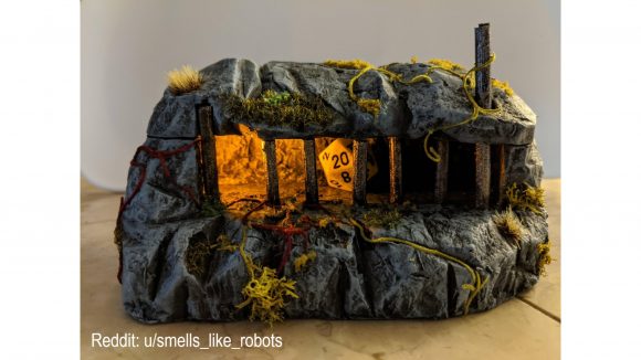 DnD Dice DIY torture device - a handmade miniature cave with space behind bars for a jail inside. The jail is lit and has a white 20-sided die inside