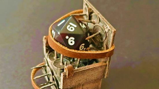 DnD dice DIY torture device - a custom-made torture chair made of card, leather straps, and thumbtacks. A d20 is strapped into the chair and forced to sit on the thumbtacks.