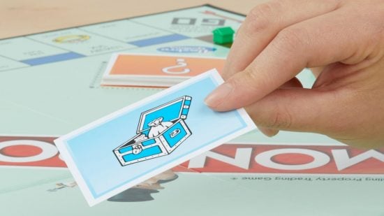 Monopoly - a hand holding a chance card above a monopoly board