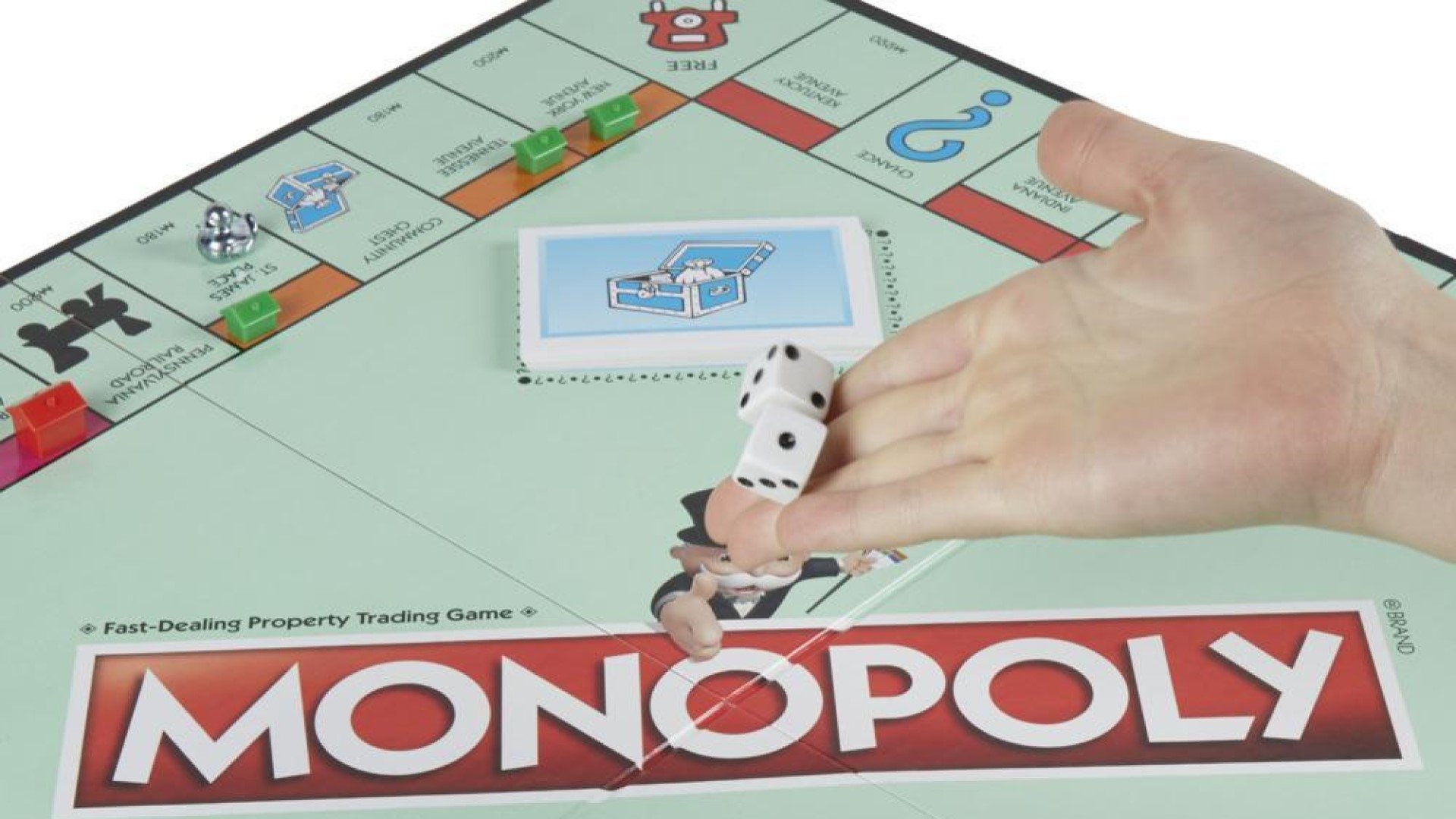 Monopoly, a hand rolling dice on a monopoly board.