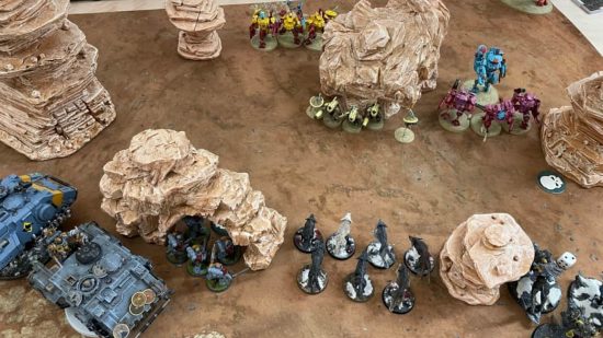 Warhammer 40k holiday home - a gaming table with Warhammer 40k miniatures fighting