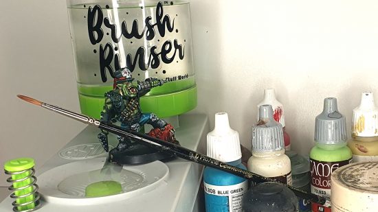 Greenstuff World Brush Rinser, a Warhammer 40k Ork Goff Rocker, a Rosemary and Co series 33 watercolour brush, and a selection of paint