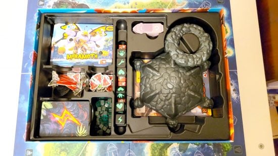 King of Monster Island board game review - author photo showing the open box, plastic insert, and game components inside, including dice, cards, and disassembled plastic volcano dice tower