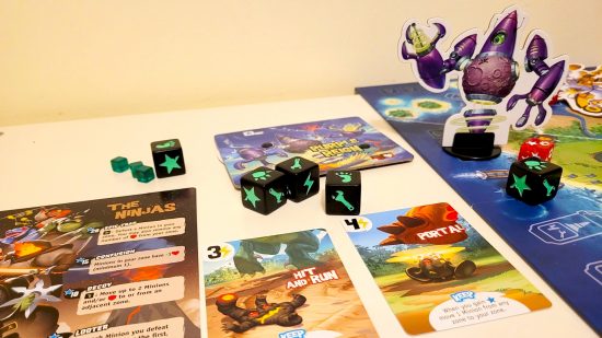 King of Monster Island board game review - author photo showing the game materials, including dice, monster standees, and Purple Reign card