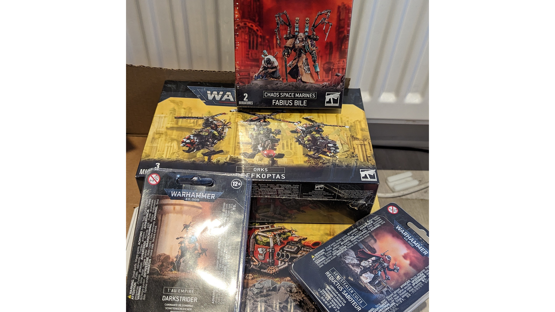 Warhammer 40k loot boxes landing - photograph of a pile of Warhammer 40k product boxes by Redditor wqwcnmamsd 