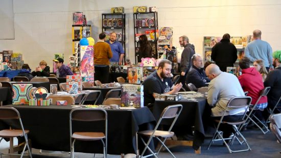 WASD 2023 tabletop zone - WASD photo showing the 2022 Wargamer tabletop zone, with gaming stalls selling tabletop games, and guests playing board games at tables