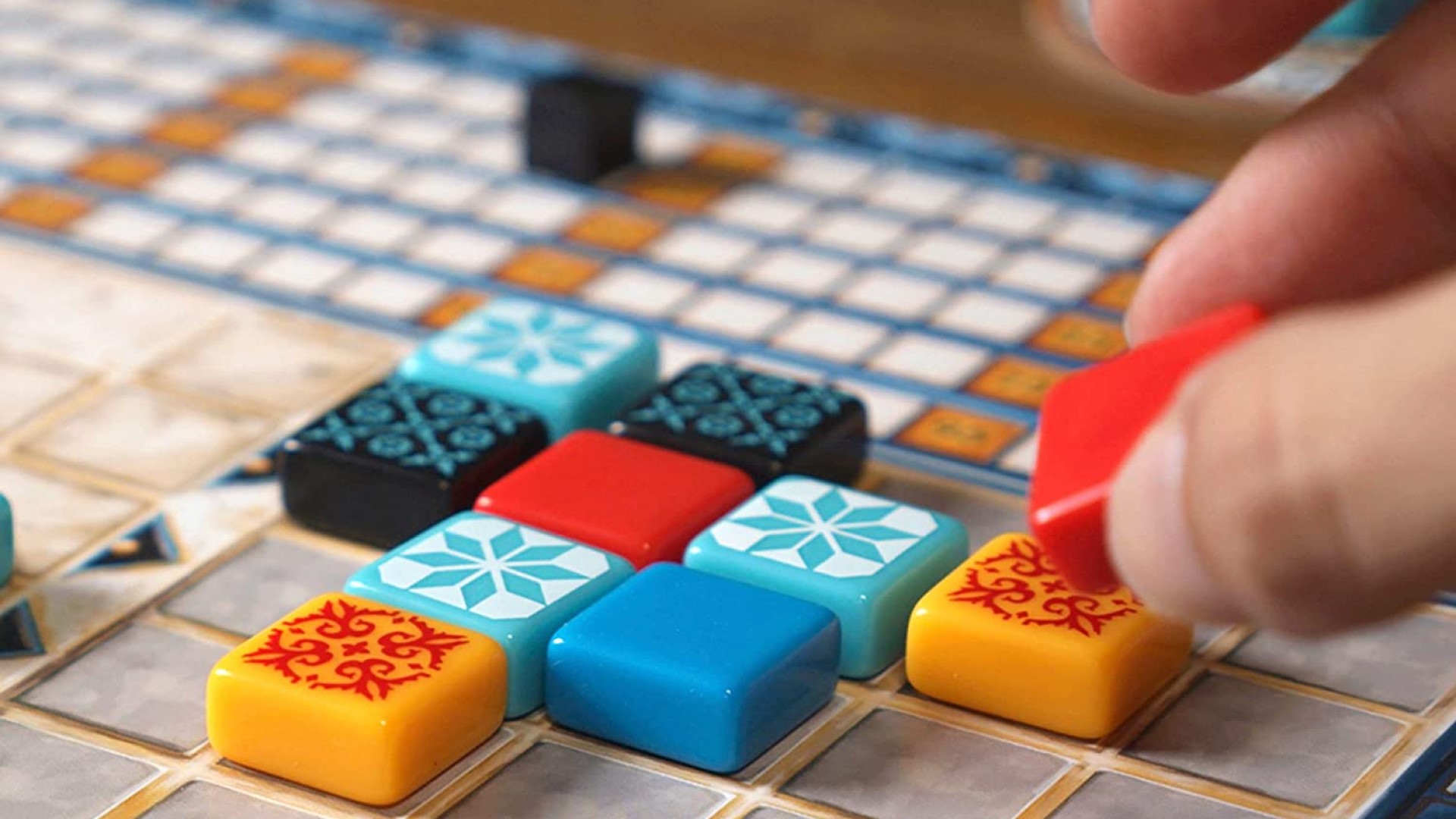 A hand laying tiles in Azul, one of the best drafting games
