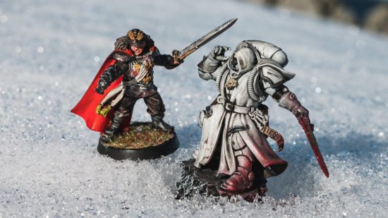 Warhammer 40k in Antarctica - photograph of an Imperial Guard commissar, a black-uniformed soldier with sword, pistol and red cape, and a white-cloaked Primaris space-marine librarian in phobos armour, on a snowfield