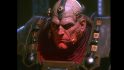 Warhammer 40k film from the 1980s, as imagined by an AI - Horus Lupercal, a glowering bald man, his face underlit with a red glow