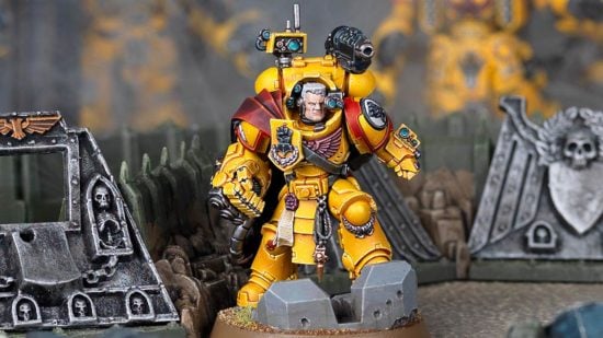 Warhammer 40k Imperial Fists Tor Garaddon, model by Games Workshop, a warrior in heavy yellow armour with a giant right fist, red cloak, and a gun mounted on his left shoulder