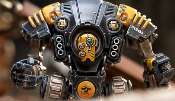 Warhammer 40k Necromunda robot - photograph by Games Workshop of a Sanctioner automaton, a beetle-backed robot with a yellow head in the centre of its torso, with a gun arm and a massive right fist
