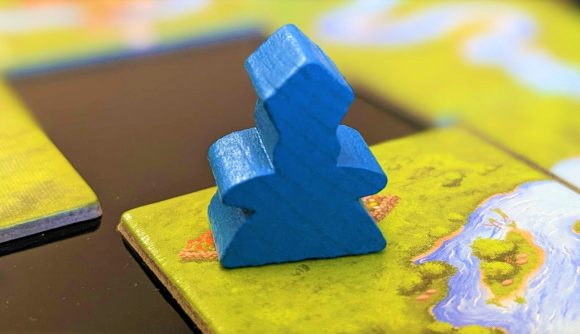 Abbot meeple on a river tile, both found in Carcassonne expansions
