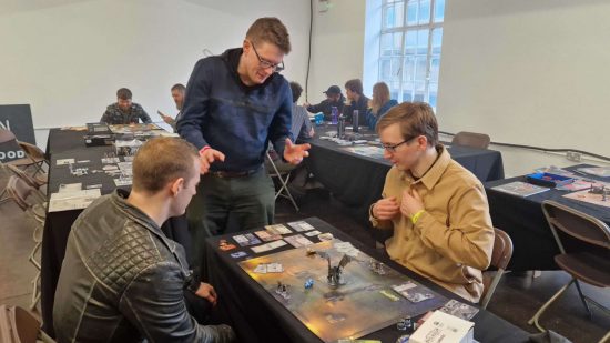 DnD Onslaught starter set review - the reviewer teaching the game to two members of the public at WASD expo