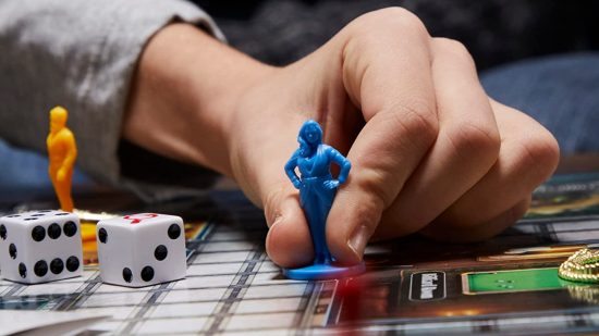 How to play Cluedo - a hand about to move a Cluedo mini