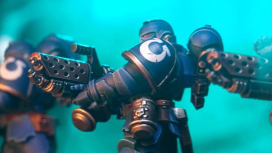 Warhammer 40k starter sets make sense at last - an Infernus marine, a blue armored warrior with a huge flame-thrower, with an inverted Omega icon on its pauldron