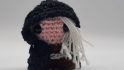 DnD mini made by crocheting of a human Rogue with long white hair and a black cloak.