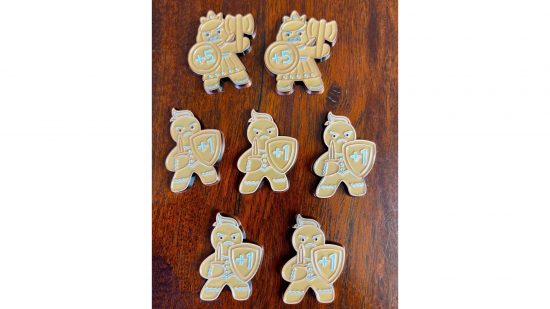 MTG Wilds of Eldraine gingerbread tokens set - Beadle & Grimm's sales photo showing three rows of plus and minus tokens from the set, looking like little gingerbread people