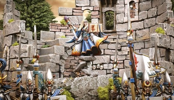 Warhammer the Old World - a High Elf wizard in blue and white robes stands atop a pillar in a crumbling tower