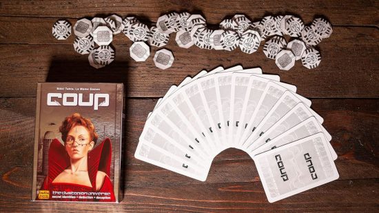 Best card games for adults guide - Coup sales photo showing the game box, cards, and tokens on a wooden table