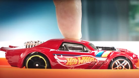 Hot wheels car being pushed by a finger above