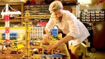 Best Lego tables guide - marketing photo showing a person wearing a flat cap leaning over a table full of LEGO in a basement, with many small shelves and drawers of LEGO behind them