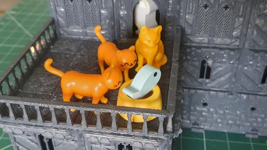Plastic cats gather on the balcony of the Scales and Ales Tavern DnD Inn kit , eating from a food bowl