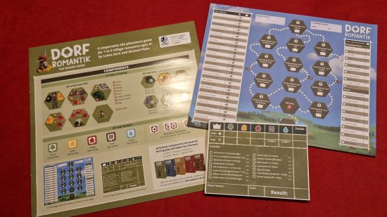 Dorfromantik Board Game review - author photo showing the game's intruction manual, game score pad, and cammpaign score pad