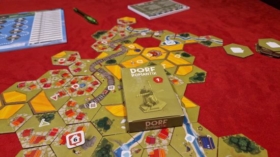 Dorfromantik Board Game review - author photo showing the game tiles laid out on the table, with a tuckbox laid over the tiles, and a game score sheet in the background