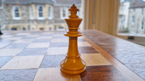 How to play Chess guide - Wargamer original photo showing a white king piece on a wooden chessboard