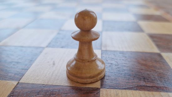 How to play Chess guide - Wargamer original photo showing a white pawn piece on a wooden chessboard