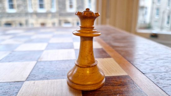 How to play Chess guide - Wargamer original photo showing a white queen piece on a wooden chessboard