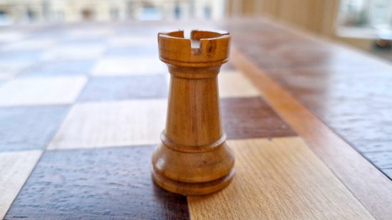 How to play Chess guide - Wargamer original photo showing a white rook or castle piece on a wooden chessboard
