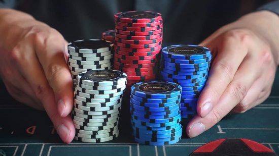 Poker rules - two hands push a pile of poker chips towards the camera