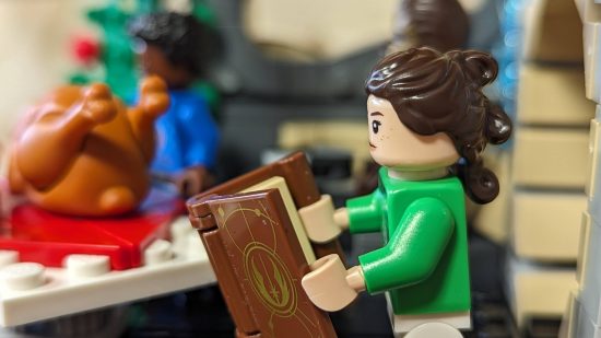 Lego Millennium Falcon review image showing Rey reading from an old book,