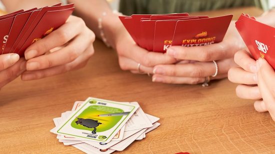 Three people playing a game of Exploding Kittens