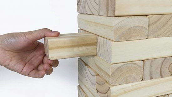 How to play Jenga - photo of a hand pulling a block from a Jenga tower