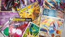 Pokemon card size and weight guide - Wargamer photo showing a jumble of different Pokemon cards laid on a table, including a Zapdos Ex