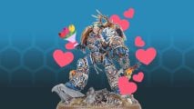 Space Marine Primarchs ranked for Vallentine's Day - Roboute Guilliman, a superhuman in blue and gold power armor, wielding a bouquet of flowers, surrounded by love hearts