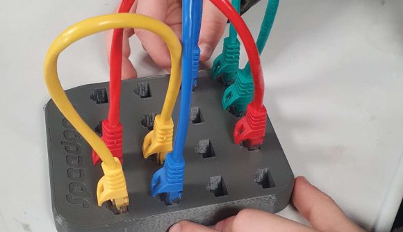Speedport board game for education - closeup on the plastic board of Speedport, with several colored ethernet cables socketed into it - a young boy's hands can be seen manipulating it