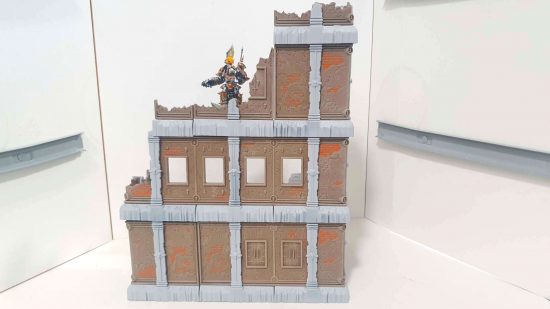 A Chaos Terminator Lord stands at the top of some Warhammer 40k terrain, a brownstone and concrete building made from FutureProof Terrain components