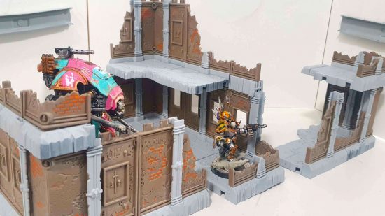 An Armiger Helverin and Chaos Lord in Terminator Armor walk through some Warhammer 40k terrain, a brownstone and concrete building by Futureproof Terrain
