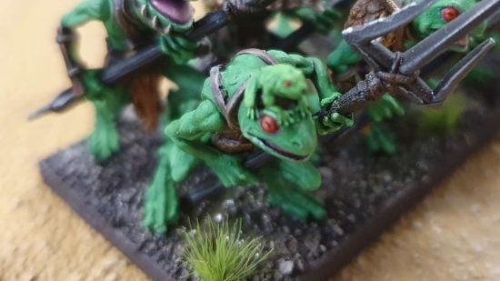A green Kings of War Riverguard frogman being ridden by a small frog