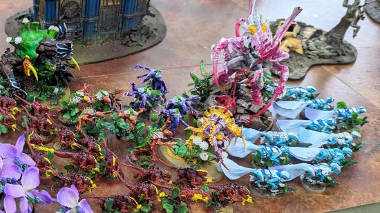 Warhammer 40k Tyranids arrmy - a horde of many-limbed aliens, with bright colored skins and shells, some of them with prominent petals around their necks or growing from their bodies